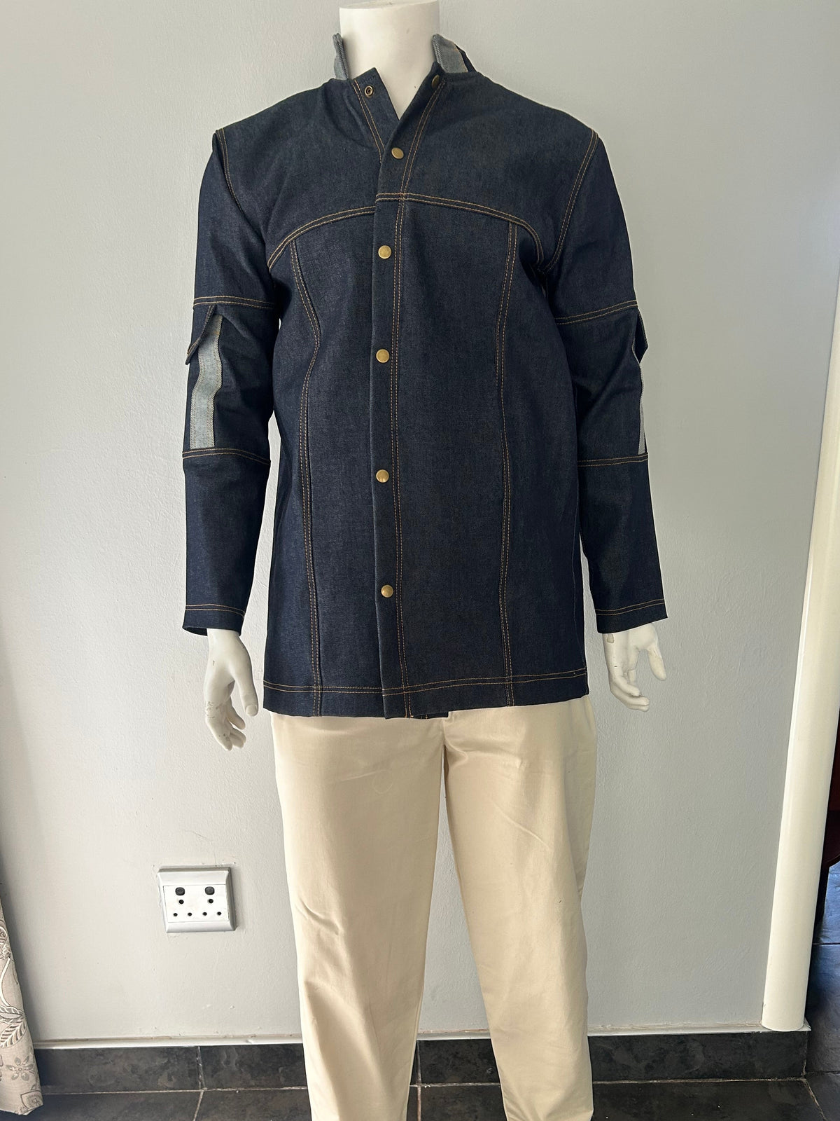 Front view of a dark blue longline denim jacket with contrast stitching and long sleeves, displayed open on a mannequin.