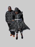 A man and a woman wearing matching black and white patterned traditional clothing walk together in a parking lot in front of a restaurant.